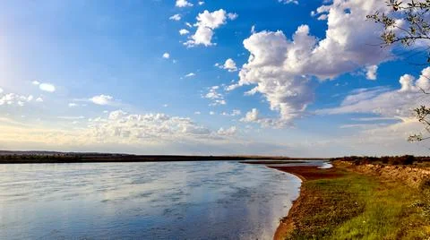 Panoramic view of the river with a calm current and cloudy sky Stock Photos