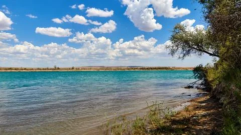 Panoramic view of the river with a calm current and cloudy sky Stock Photos