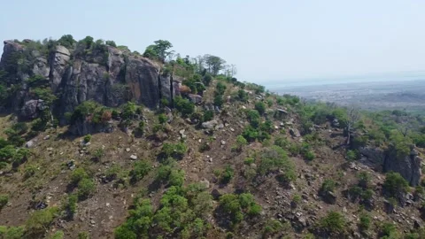 Panoramic View of a Rocky Hillside with Lush Greenery and Distant Water Body. Stock Footage 316237199