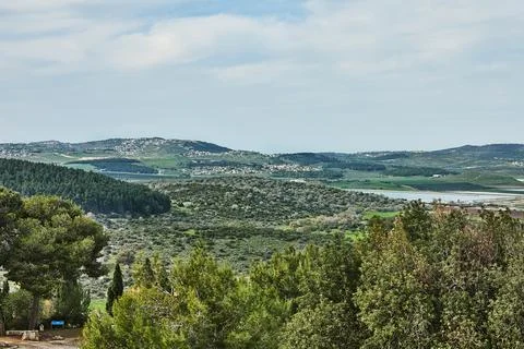 A panoramic view of rolling green fields, agricultural plots, and a distant t Stock Photos