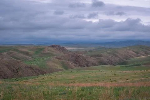 Panoramic view of rolling green hills and mountain ridges under a cloudy sky  库存照片