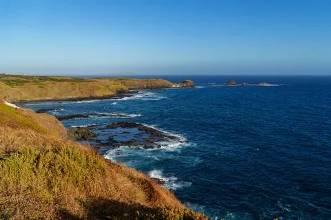 Panoramic view of a rugged coastline with dramatic cliffs, deep blue ocean .. Stock Photos