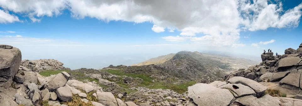 Panoramic View of Rugged Mountain Range with Distant Hikers Foto stock