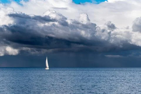 Panoramic view of a sailboat with a background full of storm clouds on lake l Stock Photos