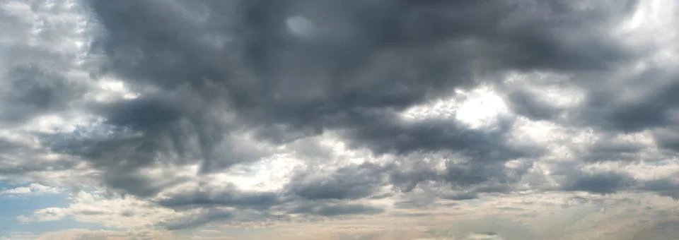 A panoramic view of scattered Dark clouds against a blue sky Stock Photos