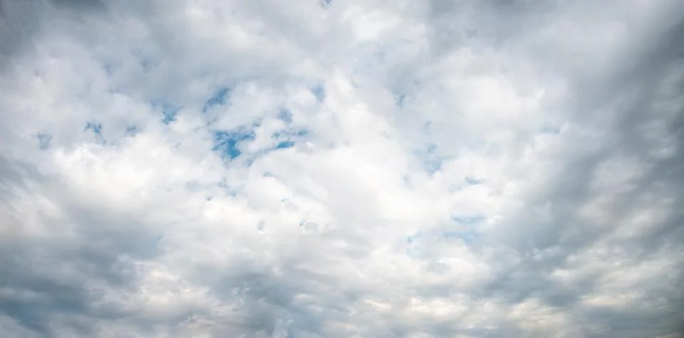A panoramic view of scattered white clouds against a blue sky Foto stock