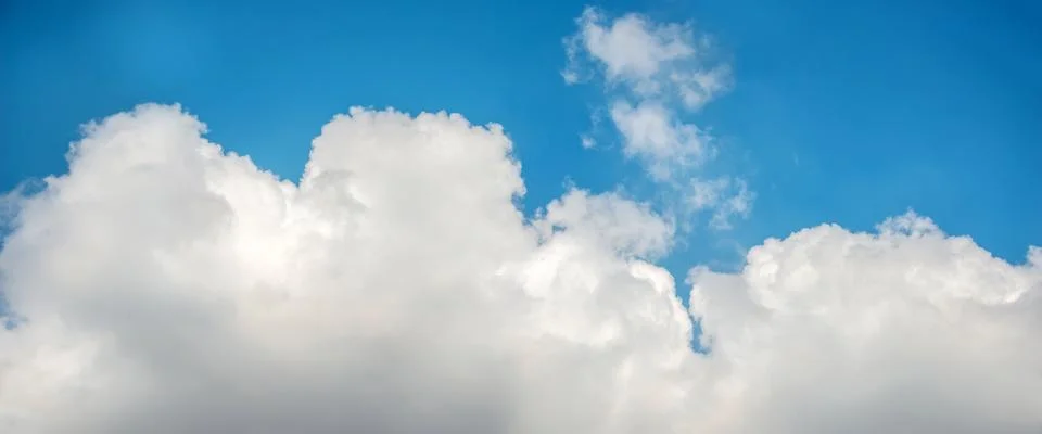 A panoramic view of scattered white clouds against a blue sky Stock Photos