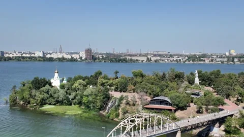 Panoramic view of a scenic park, pedestrian bridge, and river with a church Vídeos de archivo 343554055