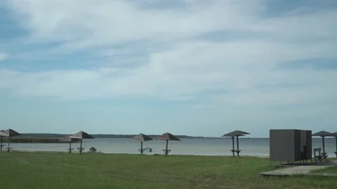 Panoramic view of the shore, beach, wooden benches, umbrella and pine trees on a Stock Footage 240738669
