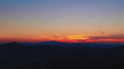 Panoramic view of silhouetted mountain ranges under a vibrant fiery sunset sky Stock Footage 347062748