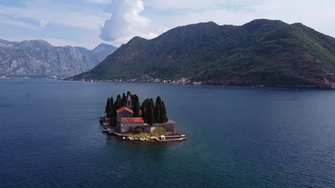 Panoramic view of small island with red roofs in bay near mountains Video stock 342770774