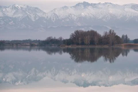 Panoramic view of snow-capped mountain peaks reflected in a calm lake at da.. Foto stock