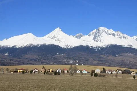 Panoramic view of snow-covered mountain peaks towering above a quiet rural Stock-Fotos