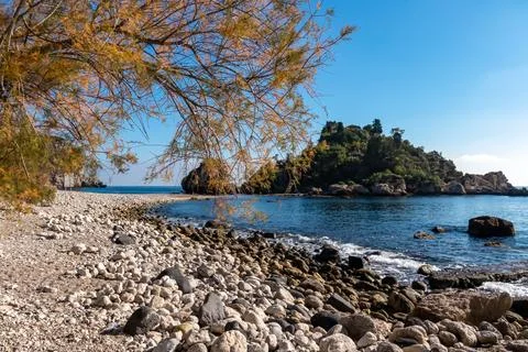Panoramic view from the stone pebble beach Spiaggia di Isola Bella on the t.. Stock Photos