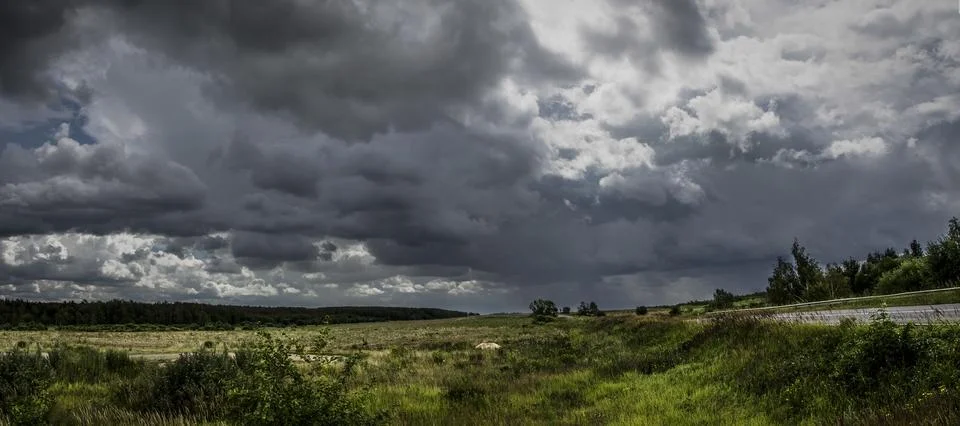 Panoramic view of stormy clouds over field in summer. Stock Photos