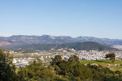 Panoramic view of a town nestled under a rugged mountain range Stock Photos