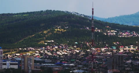 Panoramic view of a town surrounded by a dense forest with a communication tower Stock Footage 302587738