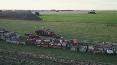 Panoramic view of a train graveyard in a field at sunset Stock Footage 217295863