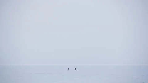 Panoramic view two people walking across the snow-covered Baltic sea 스톡 동영상 171309461