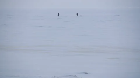 Panoramic view two people walking across the snow-covered Baltic sea 스톡 동영상 171310562