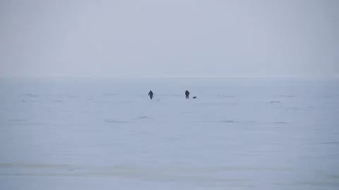 Panoramic view two people walking across the snow-covered Baltic sea 스톡 동영상 171311006