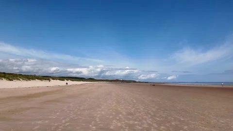 Panoramic view of the vast and beautiful Bamburgh beach under a blue sky in Видео 340912485