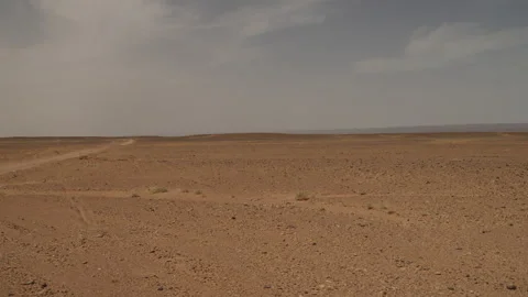 Panoramic view vast empty Sahara desert plain with dirt track under hazy sky in Stock Footage 335959862