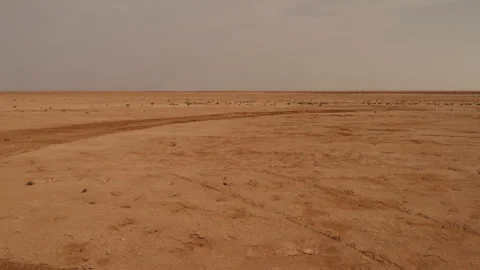 Panoramic view of vast empty Sahara desert plain with tire tracks under hazy Stock Footage 335959957