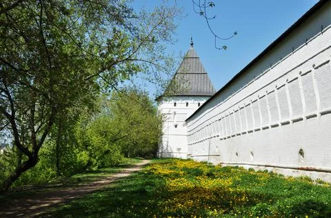 Panoramic view of the white wall of the monastery and the green lawn. Stock Photos