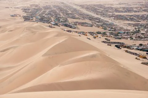 Panoramic Vista: Desert Oasis with Distant Town and Golden Sand Dunes Stock Photos