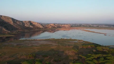 Panoramic wetland lagoon with calm reflections and rocky hills at sunset Stock Footage 344094060