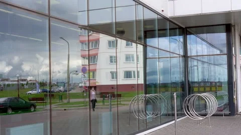 Panoramic windows of shopping centre reflect people and sky Stock-Footage 134998963