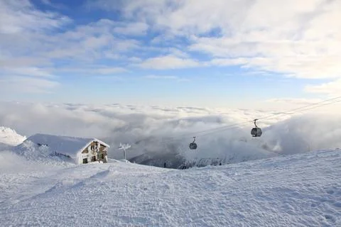 Panoramic winter mountain scene with snow-covered ski resort, cable car gondolas Stock Photos