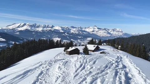 A panoramic winter scene featuring traditional wooden chalets nestled on a snowy Stock Footage 346679360