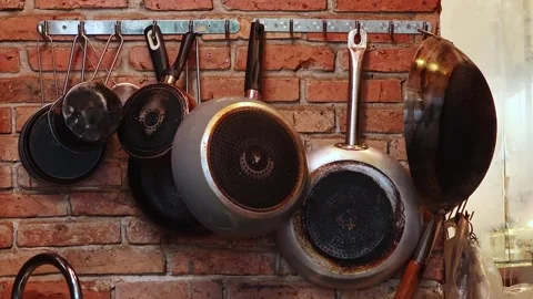 Pans hanging on brick kitchen wall, cooking utensils display Vídeo Stock 343947351