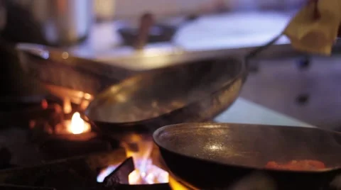 Pans sizzling open flame food preparation kitchen chef Stock Footage