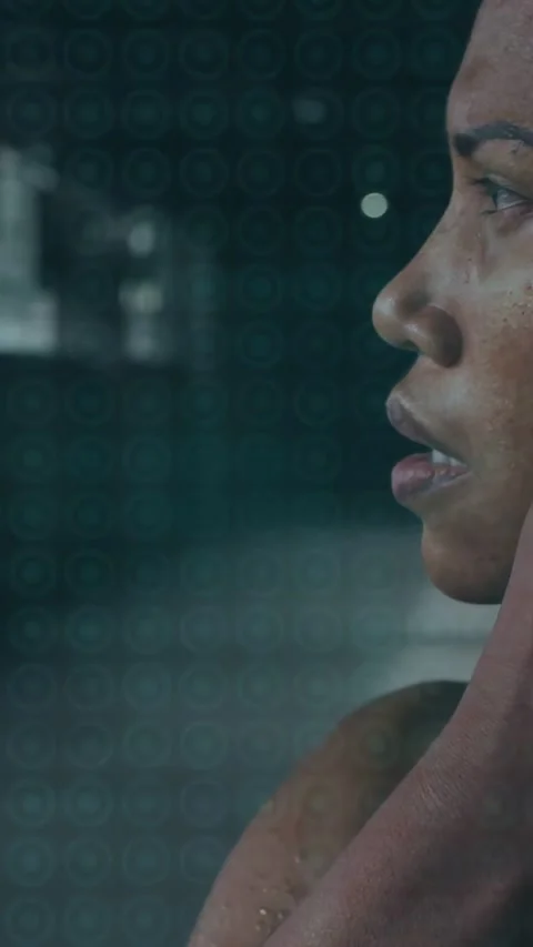 Panting, woman adjusting wired earbud, turning to camera at gym in sports tank Stock Footage 334317236