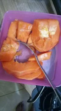 Papaya and fork on a plastic box Stock Photos