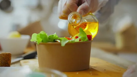 Paper bag. A cook dressed in overalls concentrates on adding oil while in lo Stock Footage 278408499