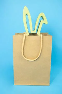 A paper bag with Easter bunny ears sticking out of it on a blue background. Stock Photos