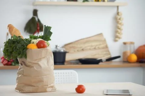 Paper bag full of vegetables on the table in kitchen interiors. Healthy meal and 스톡 사진