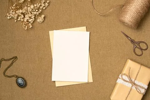 Paper blank sheet with string, scissors, gift box and flowers on fabric backg Stock Photos