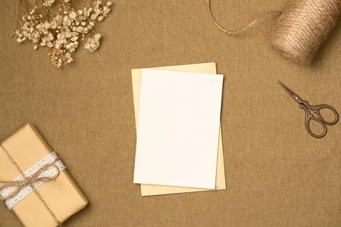 Paper blank sheet with string, scissors, gift box and flowers on fabric bac.. Stock Photos