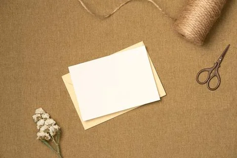 Paper blank sheet with string, scissors and flower on fabric background from  Stock Photos