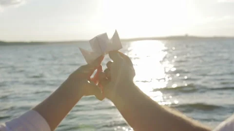 Paper boat in the hands of lovers floating on a sunny path Stockbeeldmateriaal 93424116