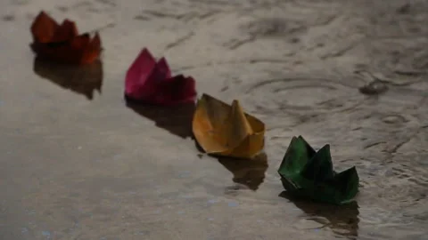 Paper boats in a puddle in the rain Stock Footage 94288301