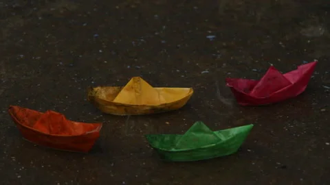 Paper boats in a puddle in the rain Stock Footage 107039324