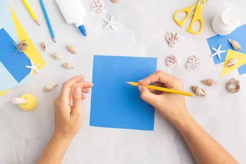 Paper bucket of shells summer idea for kids craft in kindergarten hands ocean's Stock Photos