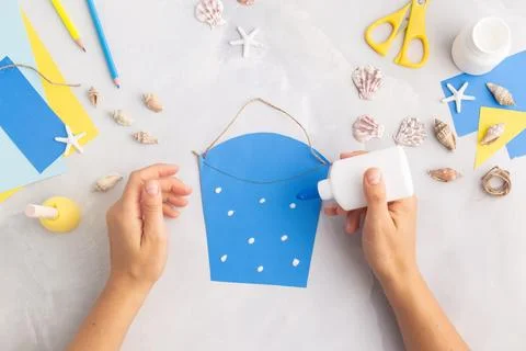 Paper bucket of shells summer idea for kids craft in kindergarten hands ocean's Stock Photos