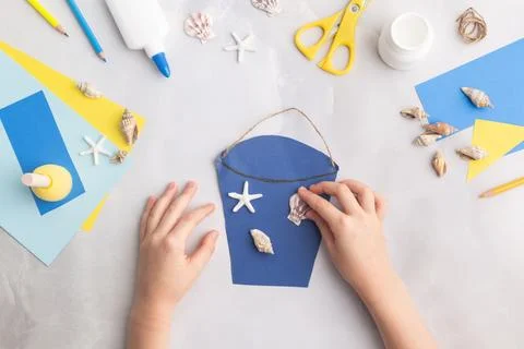 Paper bucket of shells summer idea for kids craft in kindergarten hands ocean's Stock Photos